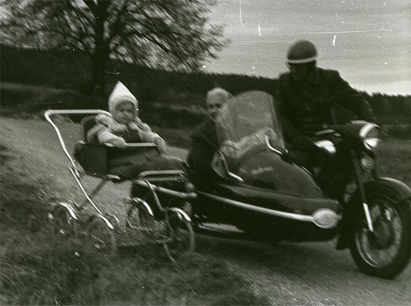 deda_na_sajde.jpg - Na úvod fotografie z doby, kdy byl ředitel firmy L.N.D. ještě na houbách. Píše se rok 1970. 
Fotka zachycuje sestru p.ř. v dobovém sportovním vozidle. A hlavně zaznamenala jeho prarodiče na krásné sajdě Velorex spřežené s Panelkou 250. 
Tu si děda pořídil fungl novou z Mototechny, poté co odložil nespolehlivou sajdu kapitalistické výroby - válečnou kořist značky BMW. Bohužel ji odložil tak, že už se nikdy nenašla ...